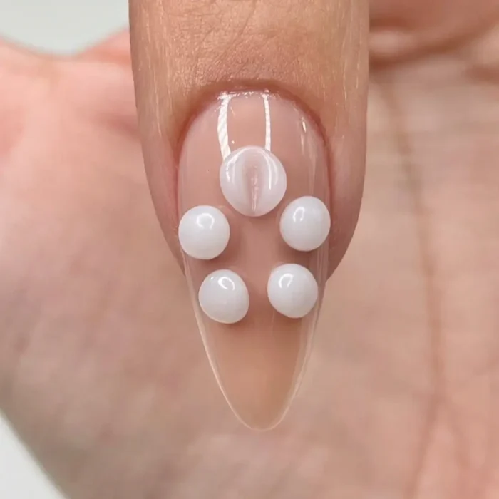An in-progress shot showing a fine-tipped brush beginning to press and shape the first bead of gel into a petal.