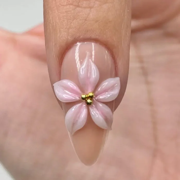 The final, completed 3D flower nail art, featuring a delicate pink flower with three tiny gold beads in its center.
