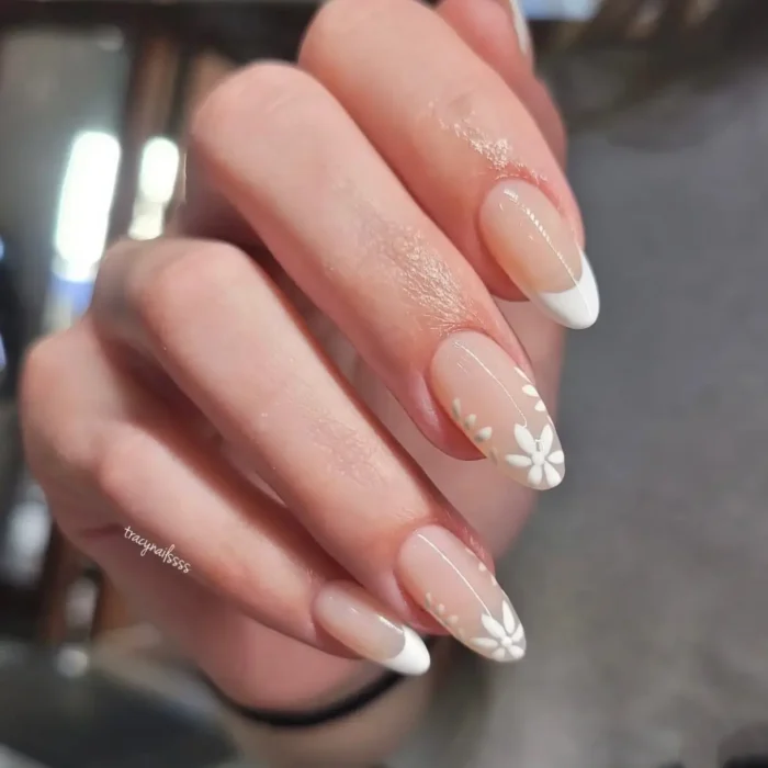 A simple white nail design on long almond nails, combining a French manicure with translucent white floral accent nails.