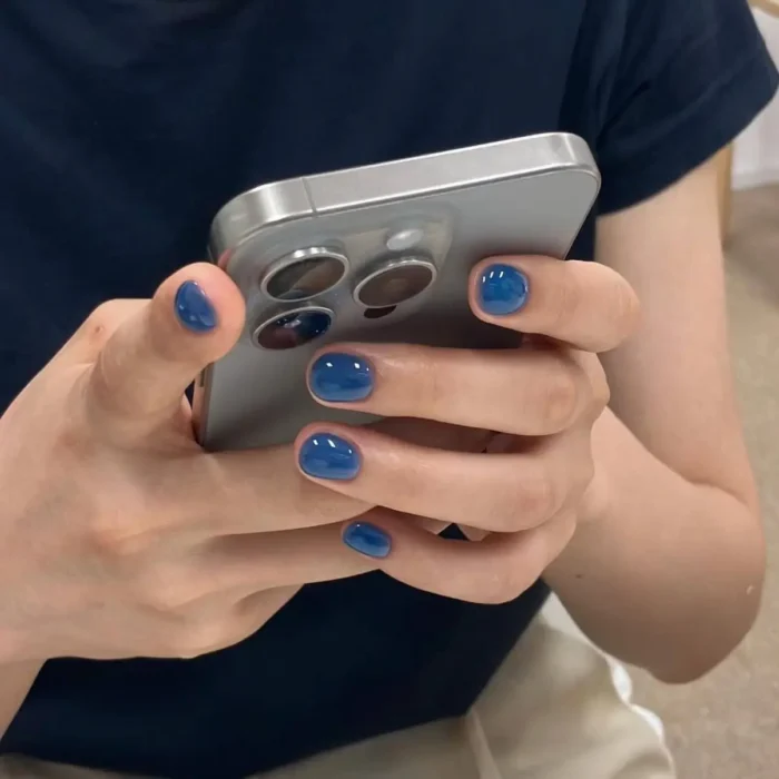 Short, neatly manicured nails coated in a glossy, deep ocean blue gel polish.