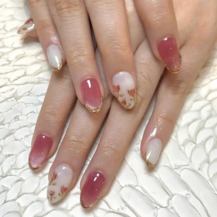 A mixed manicure with pink cat eye nails and floral accents, all framed with a gold cuff.
