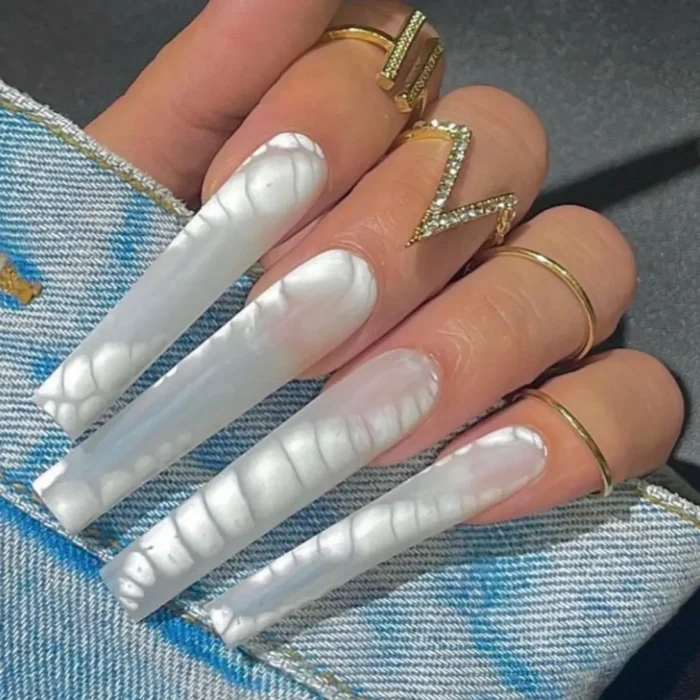 A close-up of a simple white nail design on extra-long nails with a liquid pearl, iridescent effect.