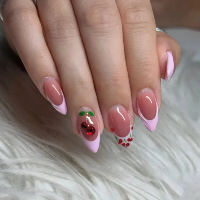 Pink stiletto nails with French tips, featuring one nail with a 3D cherry and another with scattered small red berries.
