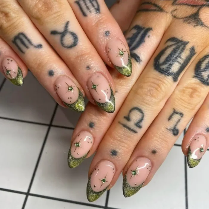 A close-up of almond nails with a chartreuse glitter french tip and gold starburst stud accents.
