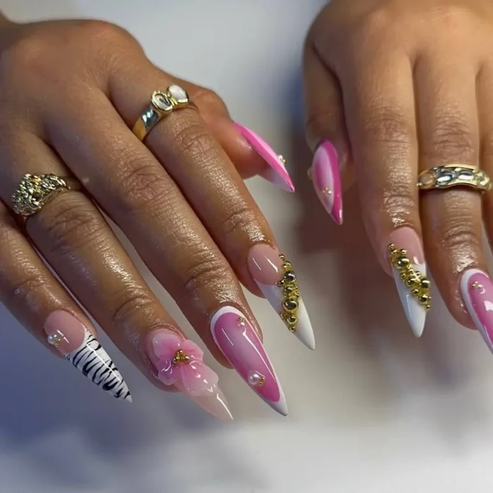 Long stiletto nails with pink and white swirl designs, a zebra print accent nail, 3D pink flowers, gold beads, and pearls.