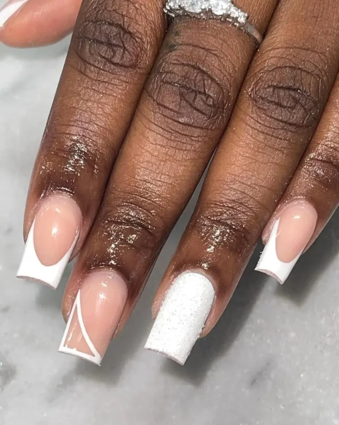 A close-up of a simple white nail art design with a mix of graphic French tips and a glitter accent nail.