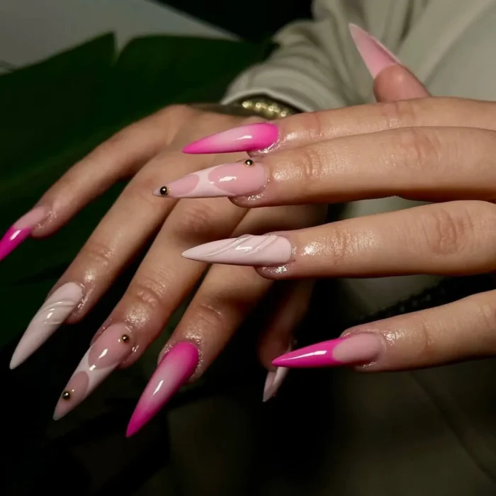 An artistic pink stiletto nail idea with ombré, 3D waves, and gold studs.