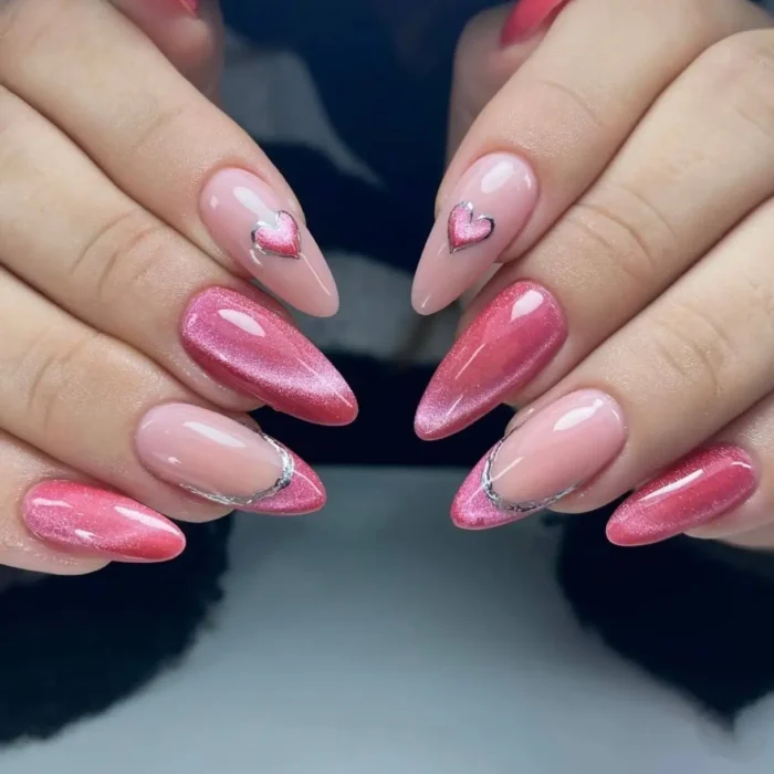 A detailed shot of almond nails with a mix of pink cat eye french tips and heart accents.