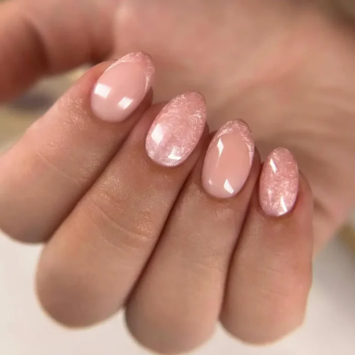 A close-up of a simple oval nail design featuring sheer pink polish with a textured velvet accent nail.