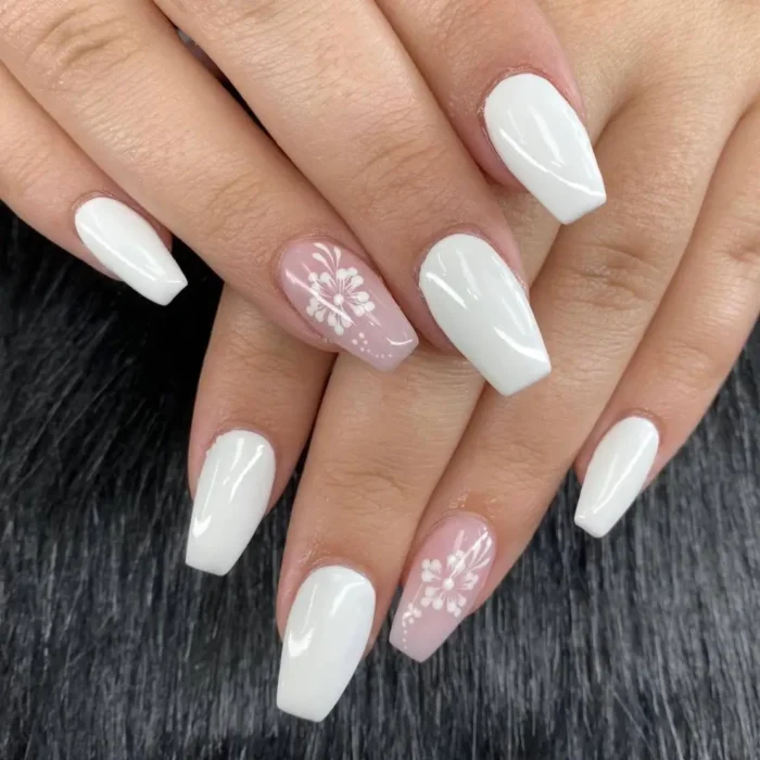 A simple white nail art design showing delicate hand-painted white flowers on accent nails.