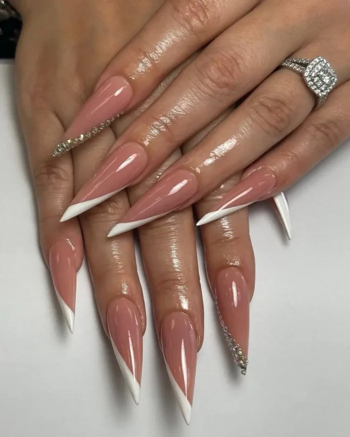 Classic pink and white French manicure on stiletto nails with a rhinestone accent.
