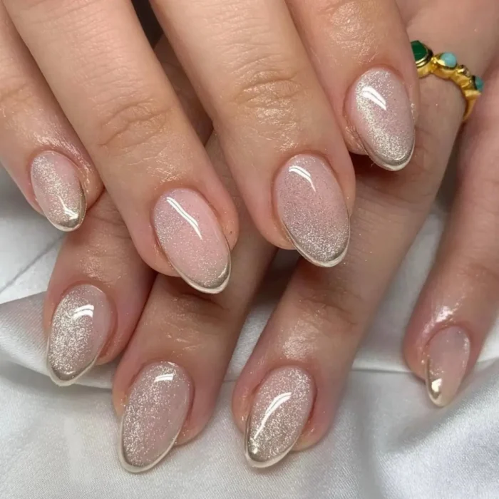 Elegant rounded nails with a platinum glitter fade and a thin metallic french tip outline.
