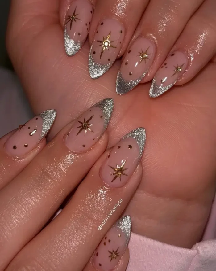 Almond nails with a silver glitter french tip and gold celestial star accents.