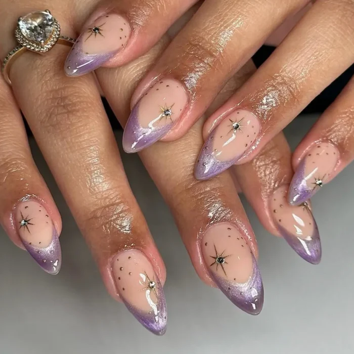 A close-up of almond nails with a lavender cat eye french tip and celestial starburst accents.