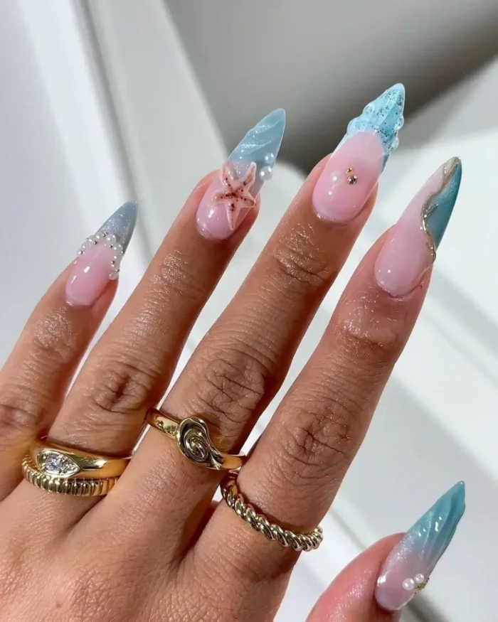 An intricate ocean-themed manicure on stiletto nails with blue crystal tips and a starfish accent.