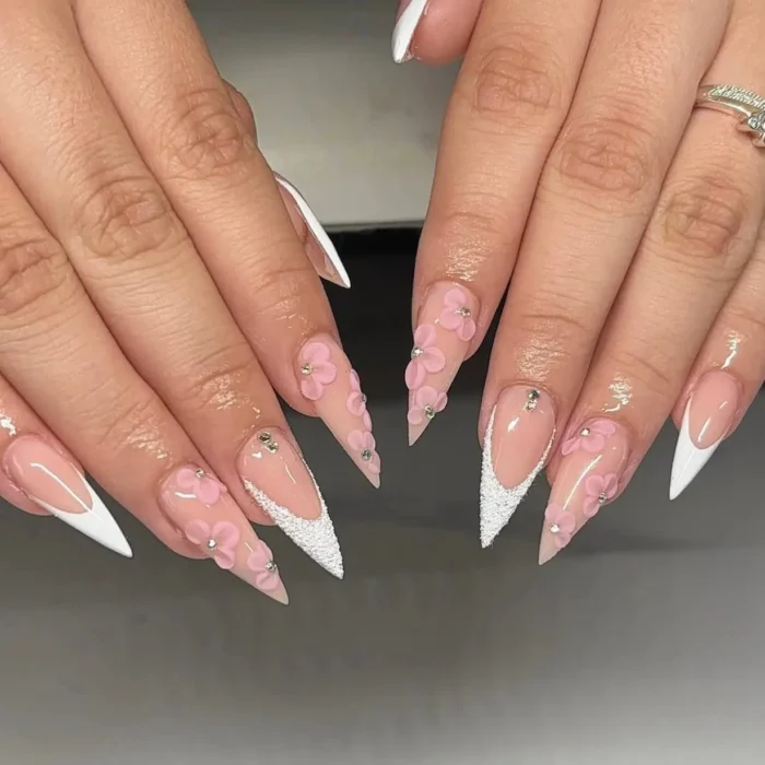 Pink and white stiletto nails with 3D flowers and a textured sugar French tip.