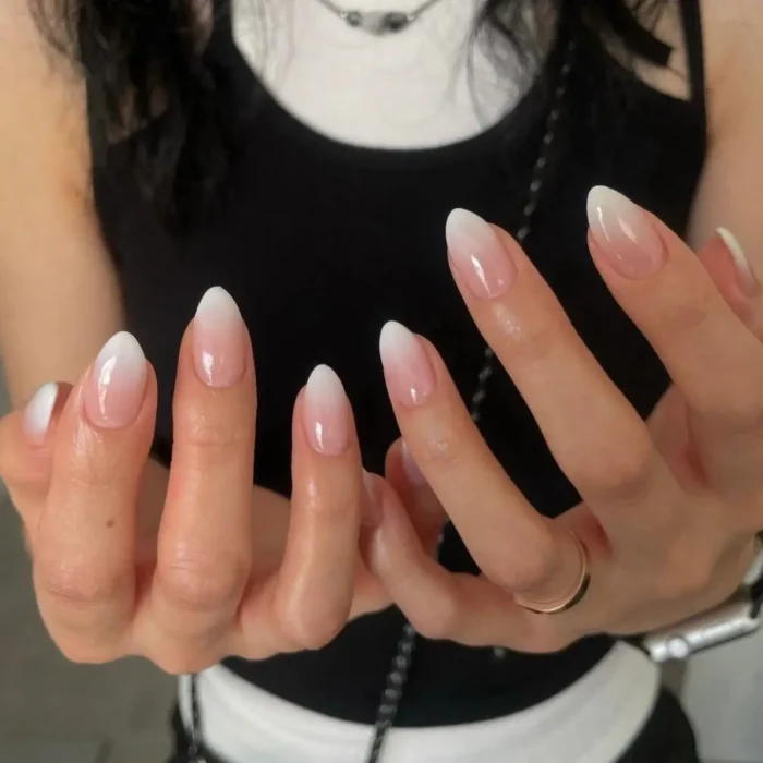 A simple white nail idea showing a classic and soft ombré design on medium-length almond nails.