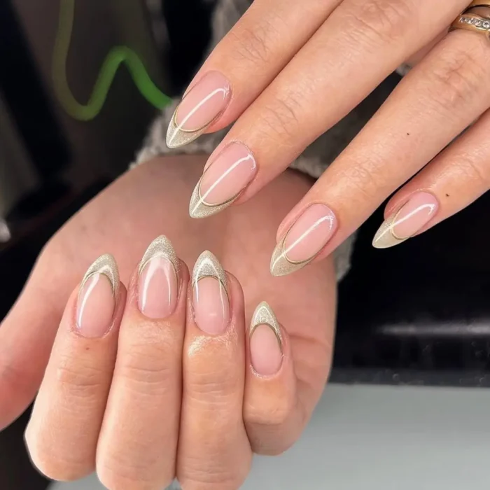 Almond nails with a champagne glitter french tip and a floating gold outline.