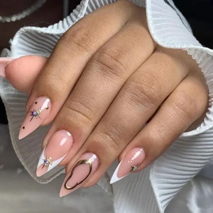 Elegant pink and white stiletto nails with gold chrome and celestial rhinestone accents.