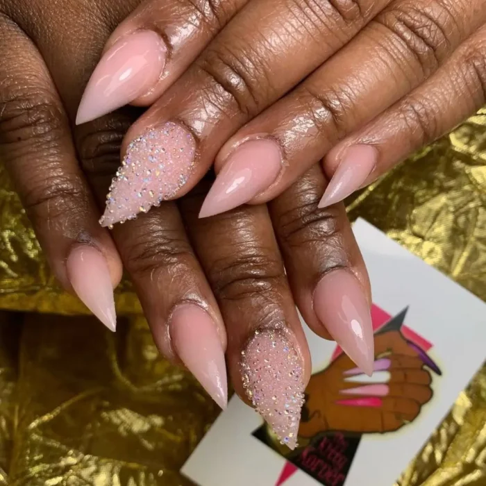 A classic sheer pink stiletto manicure with a sparkling pixie crystal accent nail.