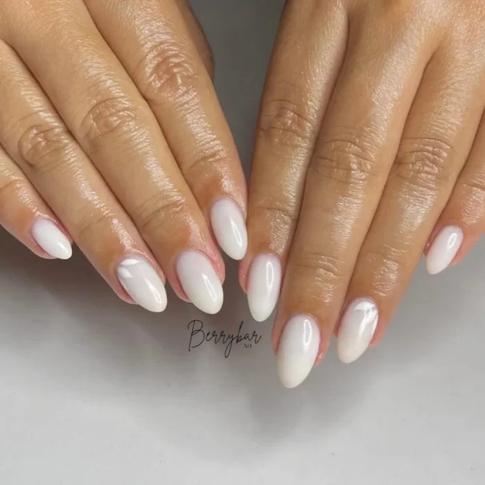 A simple oval nail idea featuring a milky white base with subtle, tone-on-tone white petal art.