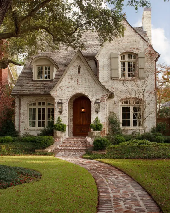 An English cottage style exterior with a timeless whitewashed brick facade and a graceful, curving walkway.